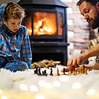 Father and son setting up game in front of fireplace